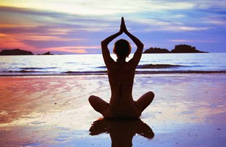日落時在海灘上練習瑜伽的女人